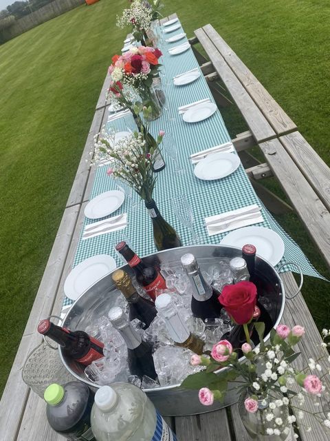 Long picnic table laid for afternoon tea with drinks on ice
