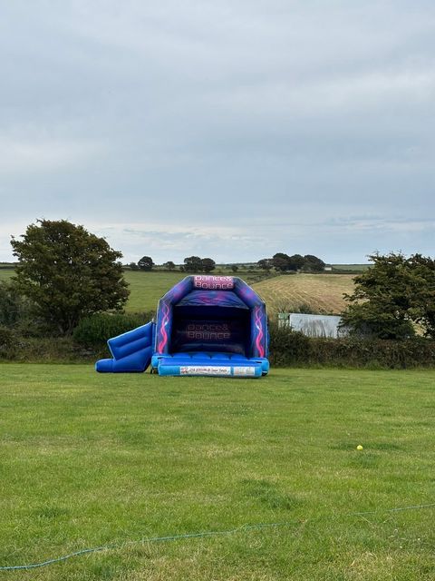 Purple bouncy castle on the lawn with fields behind