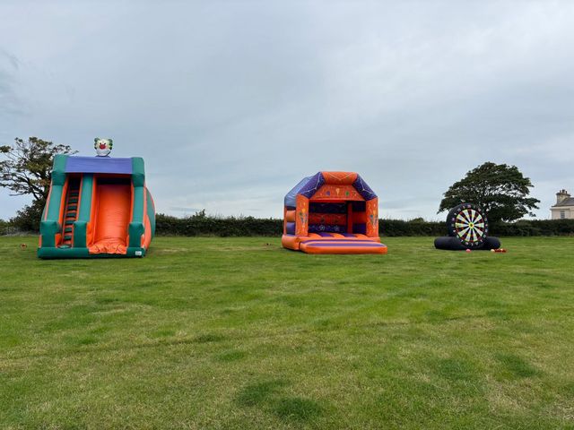 Inflatable slide, bouncy castle and giant football dartboard on the field