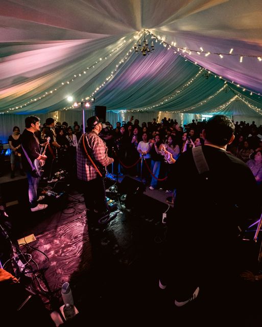 Guitarist on stage with pink lights across the marquee ceiling