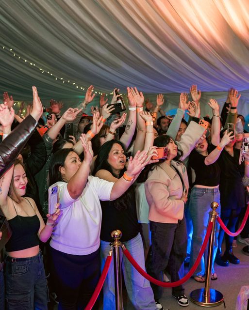 Crowd with hands raised under the marquee lights