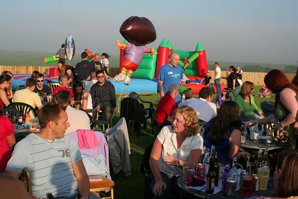 Crowd relaxing beside the inflatables at a company fun day