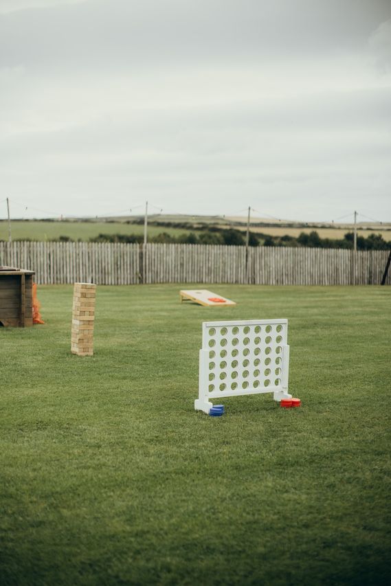 Giant connect four, giant jenga and cornhole boards on the lawn with rolling fields behind
