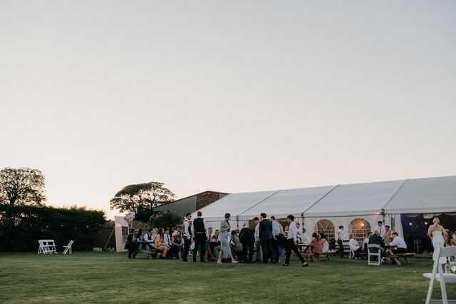 Guests gathered on the lawn outside the marquee in the evening light