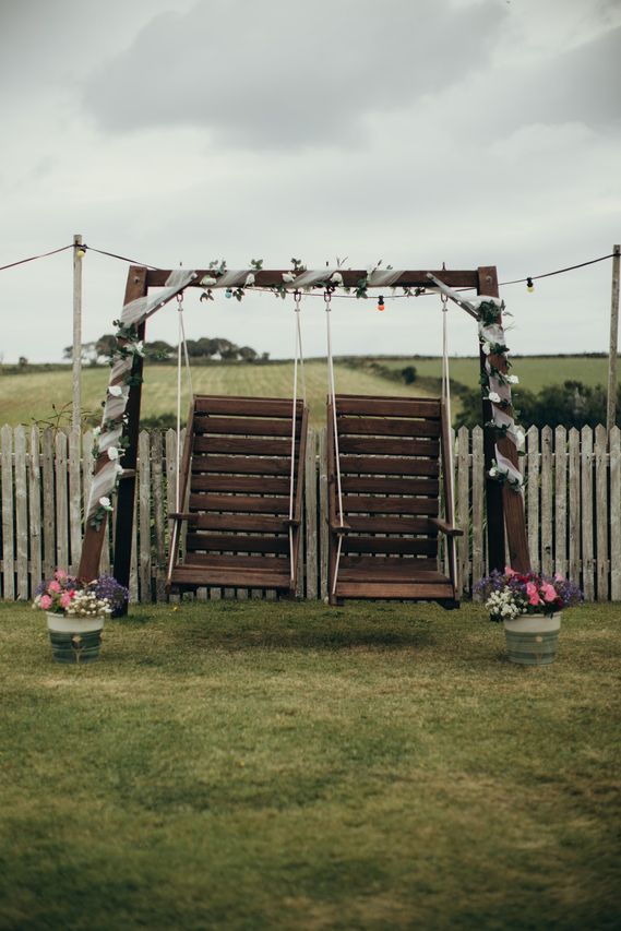 A wooden double swing seat dressed with ivy and flowers on the lawn