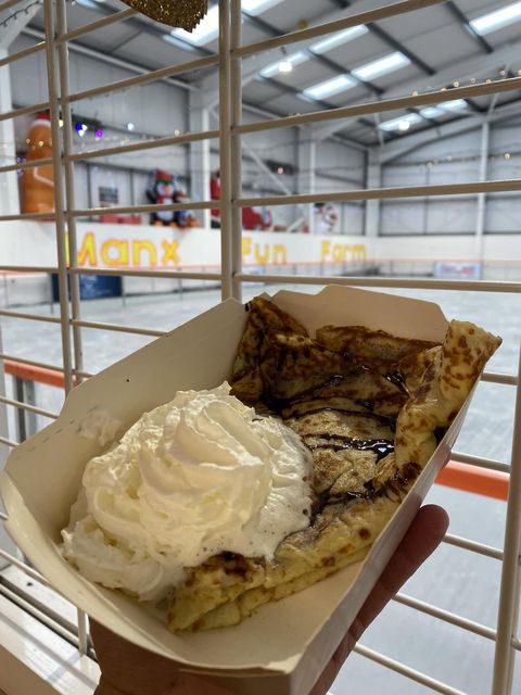 A crêpe with cream held up beside the skating rink