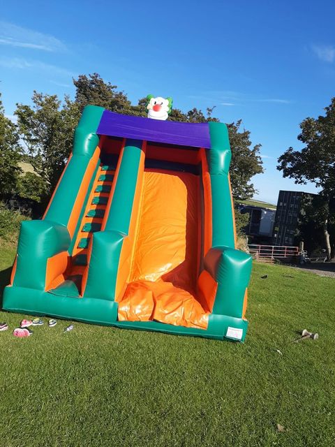 A tall green and orange inflatable slide