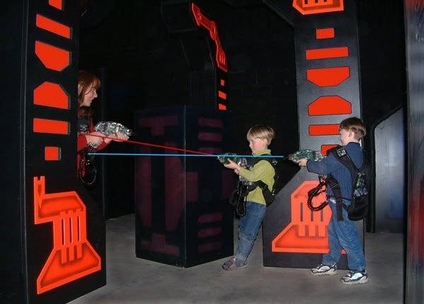 Kids in laser tag vests aiming blasters
