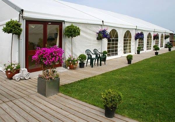 Marquee entrance with French doors, decking, potted flowers and bay trees