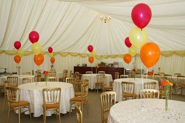 Tables in the marquee with red, orange and yellow balloons