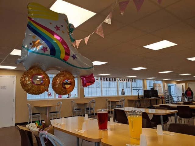 The party room with long tables, drinks and a roller-skate balloon